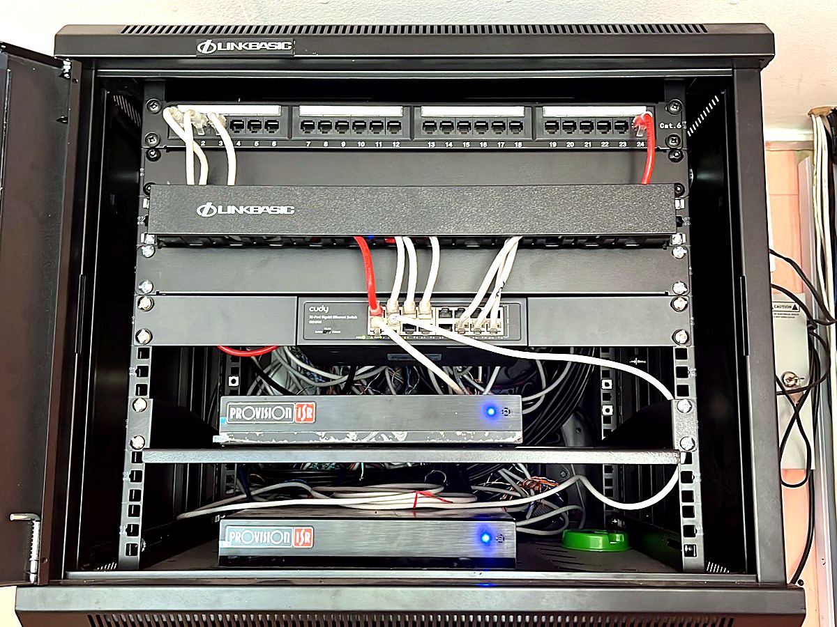 Wall-mounted cabinet with patch panels, a network switch and two Provision-ISR CCTV recorders