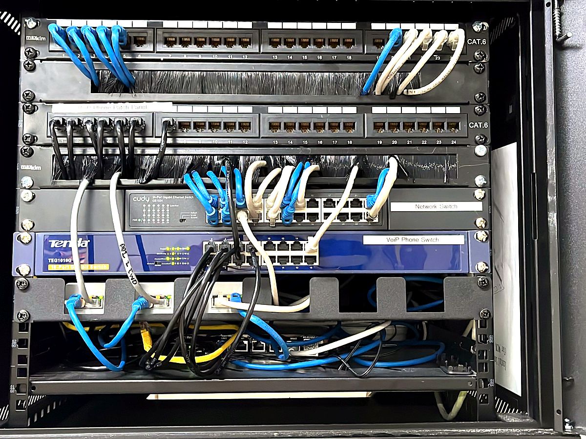 Network cabinet with patch panels, a managed switch and neatly dressed blue and white patch cables