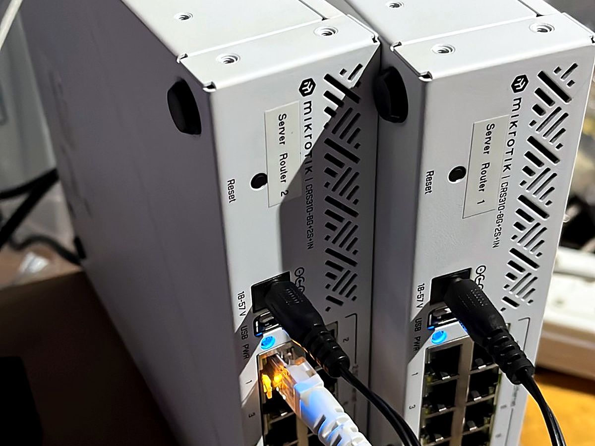 Two MikroTik routers with network cables connected, labelled for the site