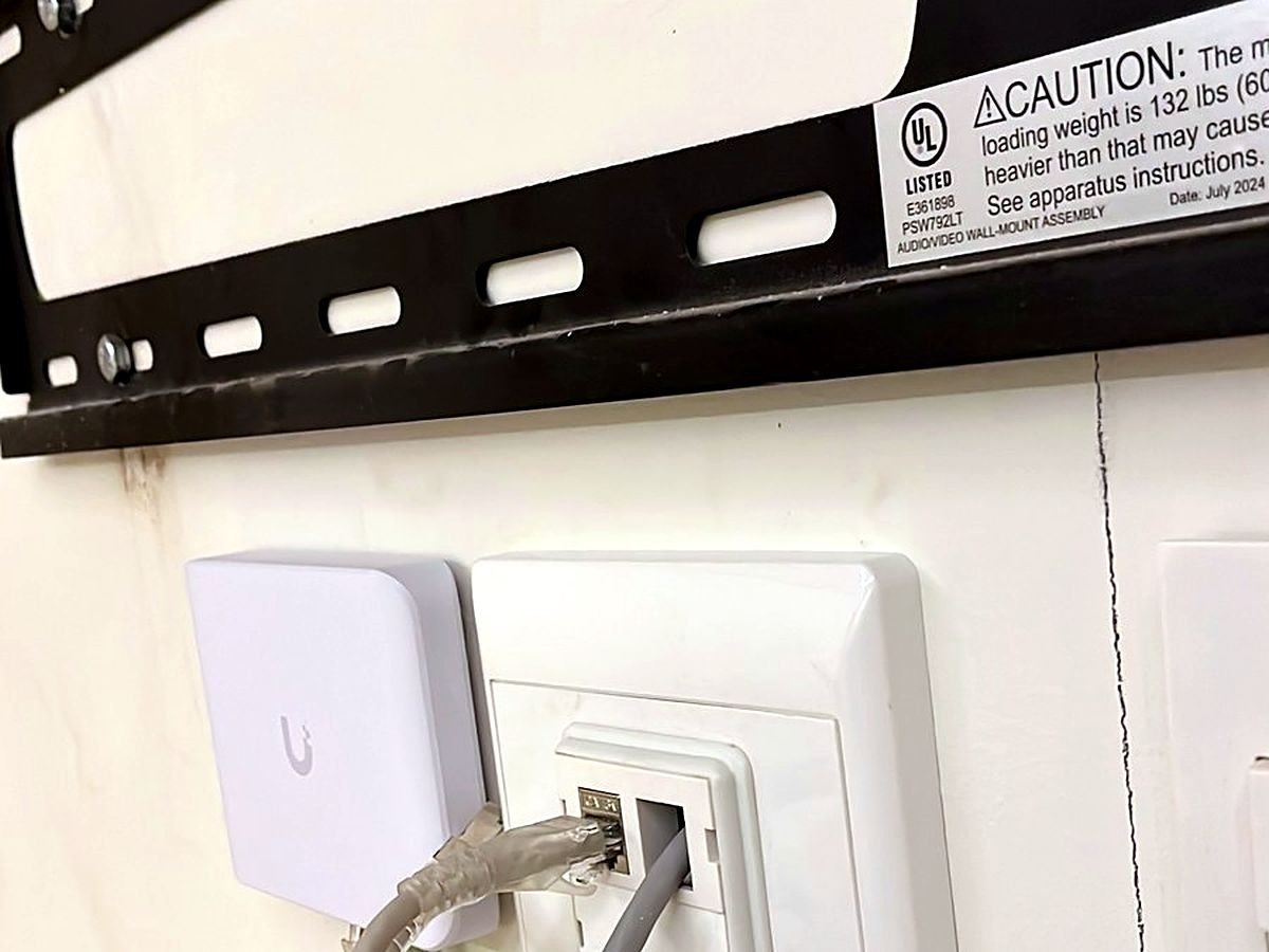 Ubiquiti UniFi Wi-Fi access point mounted on a wall next to a network data point